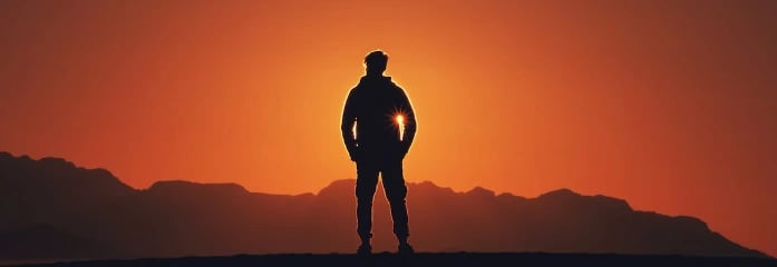 Silhouette of a person standing in front of a sunrise