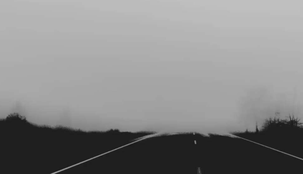 Screenshot from the Spooky video that plays - it shows a road along a wood area with fog touching down at the end, suggesting an ominous setting